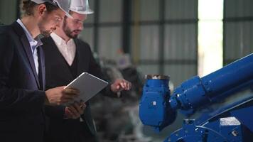 affaires ingénieurs rencontrer et vérifier contrôle lourd machine robot bras. diverse équipe de industriel la robotique ingénieurs recueillies autour machine. professionnel machinerie opérateur utilisation industriel numérique tablette. video