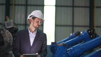 Business engineers meet and check control heavy machine robot arm. Diverse Team of Industrial Robotics Engineers Gathered Around machine. Professional Machinery Operator Use Industrial Digital Tablet. video