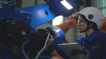 usine ingénieur femme inspecter sur machine avec intelligent tablette. ouvrier travaux à machine robot bras. le soudage machine avec une éloigné système dans un industriel usine. artificiel intelligence concept. video