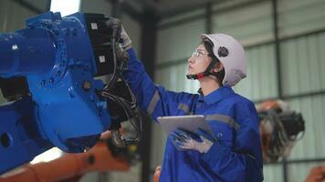 fabbrica ingegnere donna ispezionando su macchina con inteligente tavoletta. lavoratore lavori a macchina robot braccio. il saldatura macchina con un' a distanza sistema nel un industriale fabbrica. artificiale intelligenza concetto. video