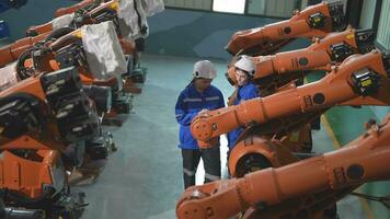 usine ingénieur femme inspecter sur machine avec intelligent tablette. femme en marchant à machine robot bras. le soudage machine avec une éloigné système dans un industriel usine. artificiel intelligence concept. video