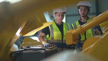 Factory engineer woman inspecting on machine with smart tablet. Worker works at machine robot arm. The welding machine with a remote system in an industrial factory. Artificial intelligence concept. video