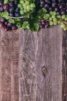 Wooden Background with Colorful Grapes and Leaves photo