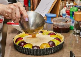 hembra panadero preparando un delicioso ciruela tarta con hecho en casa mermelada foto