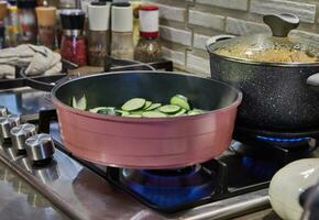 Sizzling Zucchini in a Skillet on a Gas Stove with Fire and Lid photo