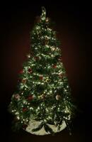 Christmas tree with decorations and garlands with lights on a dark background photo