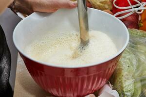 Homemaker Whisking Pancake Batter in Kitchen with Blender and Bowl photo