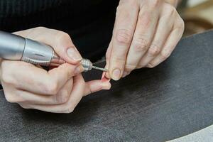 Professional Nail Technician Performing Gel Nail Extension and Manicure Using Machine photo