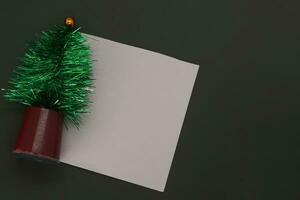 Navidad saludo tarjeta con un verde Navidad árbol y blanco sábana de papel en negro antecedentes foto