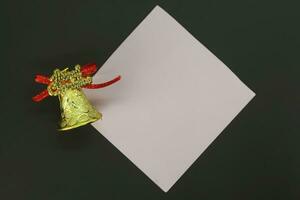 Christmas bell with blank sheet of paper on black background. Copy space. photo