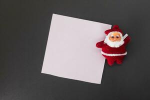 Santa Claus with blank paper on black background. Christmas and New Year concept. photo