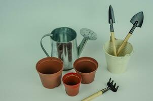 garden objects on a light background, watering can pots for planting, shovels with rakes for working in the garden and vegetable garden. High quality photo