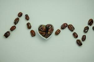 Dates lie in a white plate in the shape of a heart and laid out heart rate, healthy food concept photo