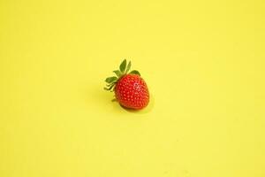 Single strawberry isolated on yellow background photo