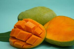 fresh mango fruit with cube slice with yellow flesh inside isolated on cutting board blue background contain vitamin C photo