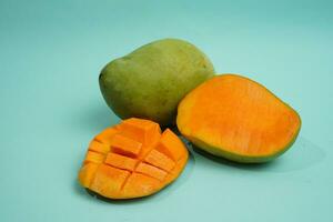 fresh mango fruit with cube slice with yellow flesh inside isolated on cutting board blue background contain vitamin C photo