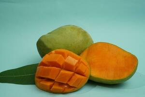 fresh mango fruit with cube slice with yellow flesh inside isolated on cutting board blue background contain vitamin C photo