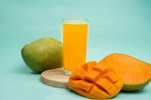 Mango drink on round tray with mango fruit on blue background photo