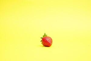 Single strawberry isolated on yellow background photo