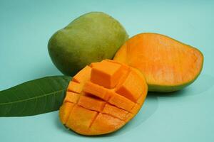 fresh mango fruit with cube slice with yellow flesh inside isolated on cutting board blue background contain vitamin C photo