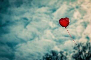 ai generado un rojo corazón globo en el aire con un rojo línea a través de eso foto