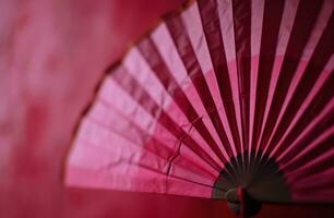 ai generado un rosado origami ventilador cuelga en un rojo antecedentes foto