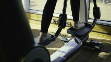 atlético niña haciendo un elipsoide en gimnasio lado vista. existencias. mujer trenes en un elipsoide foto