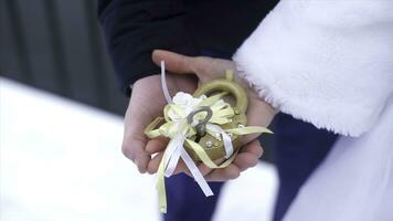 Wedding symbol, lock in hands of bride and groom. Newlyweds fix the lock on the bridge as a symbol of love. Padlock in the hands of the bride and groom. Lock in heart shape on the railing of bridge - photo