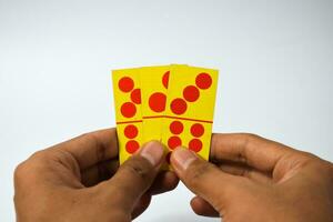 mano sostener dominó jugando tarjetas aislado blanco fondo, amarillo rojo dominó tarjetas foto