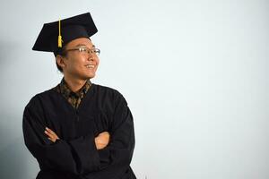 Expressive of Adult indonesia male wear graduation robe, hat and eyeglasses isolated on white background, expressions of portrait graduation photo