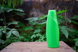 Green bottle shampoo product on a background of green leaves. Eco friendly product. photo