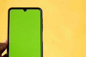 mano participación moderno móvil teléfono verde pantalla aislado en amarillo antecedentes foto