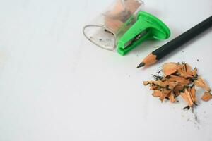 green pencil sharpener and dark green pencils, pencil shavings on white background photo