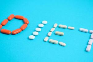 Diet word from Colorful Medicine Pills isolated on blue background, supplement, vitamin, colorful photo