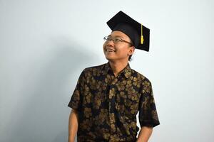 Expressive of Adult indonesia male wear batik, toga cup or graduation hat and eyeglasses isolated on white background, expressions of portrait graduation photo