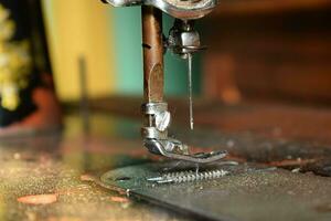 Close up sewing machine with needle on wood table, antique sewing machine with dust photo