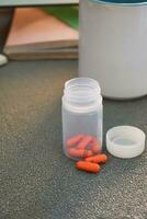 medical pill capsule and bottle with mug or glas of water on table workspace photo