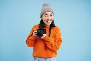 Passionate asian girl photographer, taking pictures on her digital camera, capturing moments outdoors, shooting photos, blue background photo