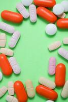 Colorful medicine pills with copy space on the center in green background photo