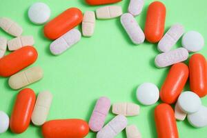 Colorful medicine pills with copy space on the center in green background photo