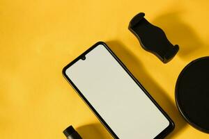 top view of smartphone with white screen and parts of stand phone or mini tripod photo