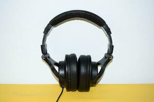 top view black headphone with cable on white and yellow background photo