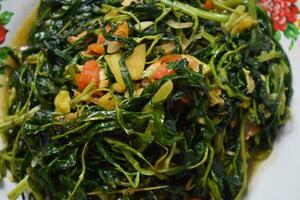 Close up stir fried spinach on white plate isolated white background photo