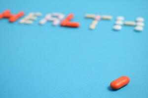 red medicine pill on health word blurred background blue, supplement, vitamin, colorful photo