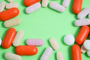 Colorful medicine pills with copy space on the center in green background photo