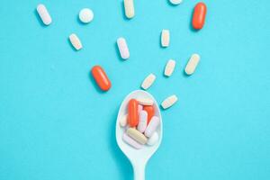 Colorful Medicine Pills in White spoon on green tosca background, supplement, vitamin, colorful photo