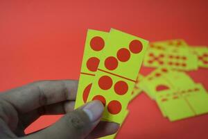 mano sostener dominó jugando tarjetas aislado rojo fondo, amarillo rojo dominó tarjetas foto