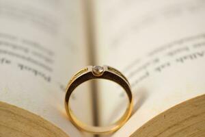 Close up golden ring with diamond between book opened photo
