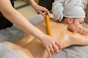 joven mujer consiguiendo un espalda masaje en un spa salón. belleza tratamiento concepto. foto