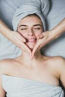 Young girl with perfect skin on a white background, towel on her head, beauty concept photo, skin care, spa concept, treatment, facial massage. photo